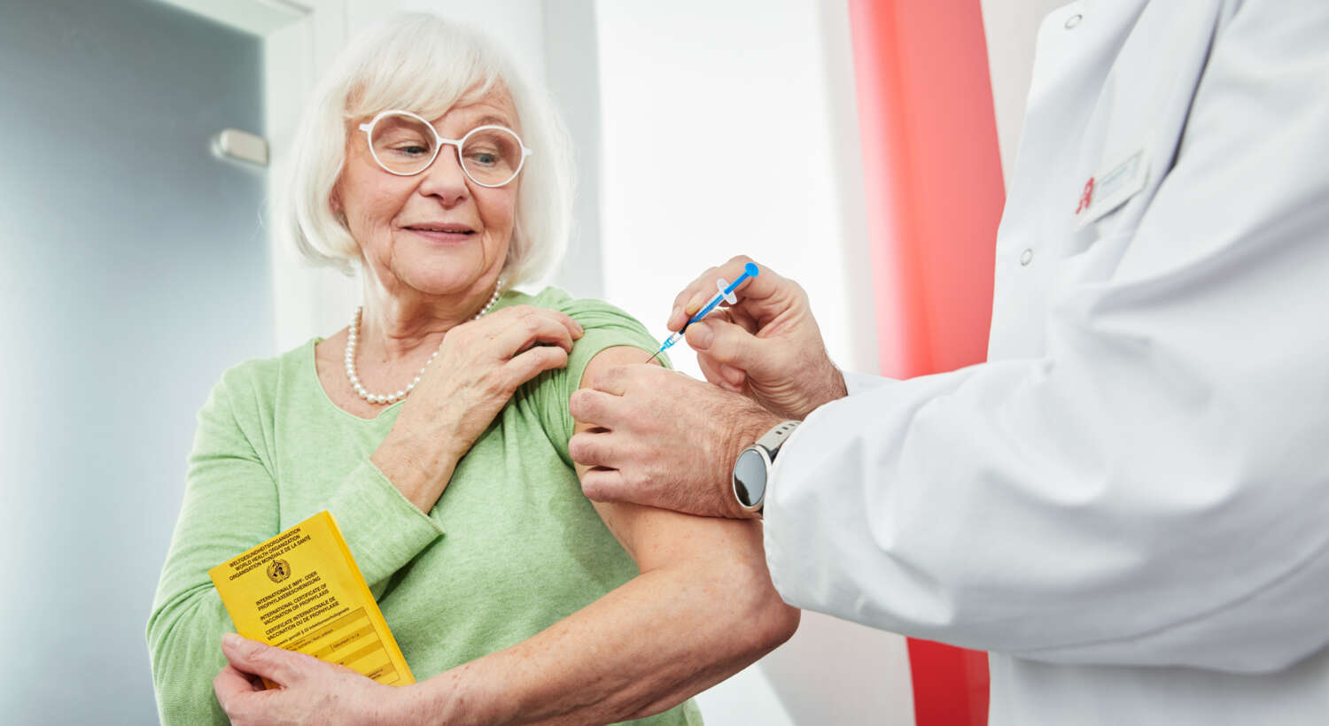 Ältere Frau bekommt Impfung in den Arm in einer Apotheke